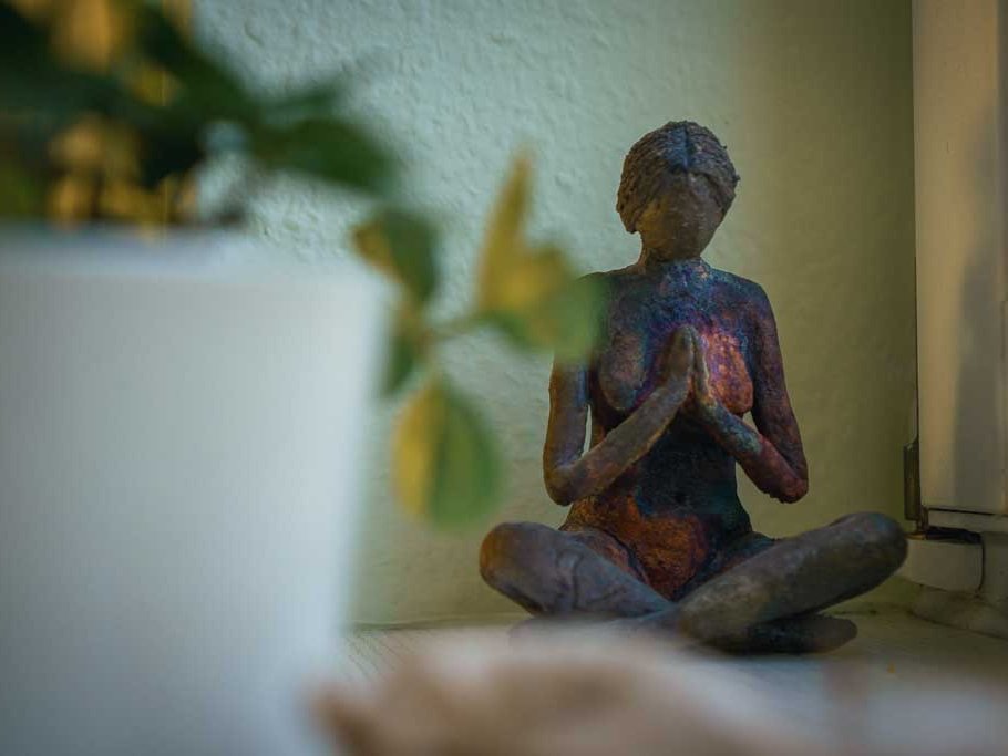 Kleine Meditationsfigur und Pflanze auf einer Fensterbank im Yogaraum